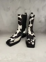 Bota de cuero con estampado de vaca en blanco y negro, taco bajo y elástico lateral.