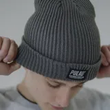 Gorro de lana blanco con etiqueta negra con el logo de la marca Pulau.