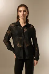 Camisa negra de poliamida con diseño calado de encaje floral, corte holgado, cuello camisero, botones frontales y mangas largas.