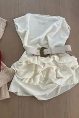 Minifalda color crema con textura arrugada, cintura alta con cinturón y volados en el ruedo.