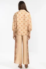 Pantalón palazzo color beige con estampado de girasoles marrones en los laterales.