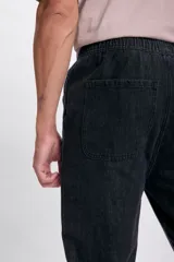 Pantalón jogger de jean color gris oscuro, con cintura elástica y cordón ajustable. Corte holgado con puños elásticos en los tobillos.