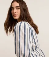 Blusa de sarga a rayas verticales blancas y azules, con cuello en V, mangas cortas abullonadas, lazo en la cintura y volado en el bajo.