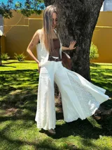 Pantalón blanco de corte palazzo con aplicaciones de encaje floral en los laterales.