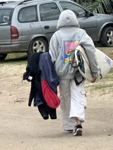 Canguro negro con capucha y cordones ajustables. Estampa en la espalda con el texto "Chema Surf Trip" y dibujos de un sol, una tabla de surf, una carpa y otros elementos relacionados con el surf.