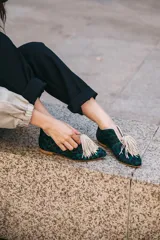 Botines bajos con estampado animal print en tonos verde y negro, con escote en V y borlas decorativas en el empeine.