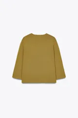 Chaqueta color mostaza de tejido de punto, con cuello redondo y manga tres cuartos. Tiene bolsillos delanteros de parche y cierre frontal con botones dorados.