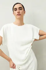 Top blanco de tejido texturizado con cuello redondo y mangas cortas tipo murciélago.