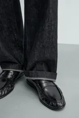 Mocasín de vestir negro con antifaz, de punta fina y suela a tono.