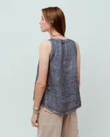 Top sin mangas blanco de lino, con escote redondo, corte en A, ruedo asimétrico y recortes laterales.