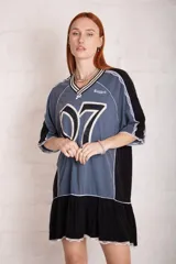 Vestido corto tipo remera deportiva, con parte superior gris con estampado del número 07 y la marca Ragged, cuello en V a rayas blancas y negras, mangas cortas con detalle de encaje y falda negra con volado y encaje en el ruedo.