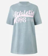 Remera de algodón con efecto desteñido, color verde azulado, corte holgado y cuello redondo. Presenta un estampado frontal en color rosado con el texto "Athleti 1998" y una línea horizontal.