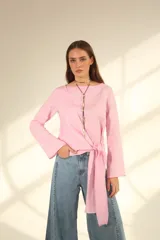 Blusa blanca de lino con escote en V cruzado, mangas largas y lazo en la cintura.