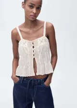Top blanco con tirantes finos, cierre de botones en la parte delantera, cuello escotado, diseño recto, detalles calados y tejido de punto medio.
