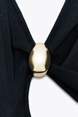 Vestido midi negro de punto con escote pico, tirantes finos cruzados en la espalda, aplique dorado y abertura en la cintura.