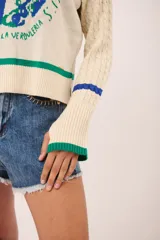 Sweater azul marino de punto con cuello redondo y mangas largas con diseño trenzado. Presenta un estampado de frutas y verduras con la inscripción "La verdulería S.A.".