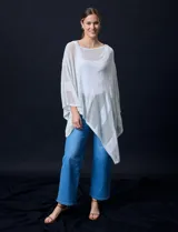 Poncho negro de tejido calado con lurex, terminación asimétrica y cuello redondo.