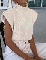 Chaleco de punto color crema, con cuello alto y corte holgado.