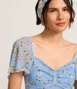 Blusa cropped de tule celeste con estampado floral, escote corazón, mangas cortas sueltas con acabado frufru y fruncido en el busto.