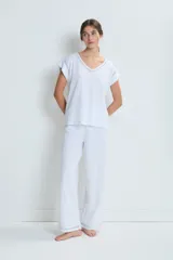 Conjunto de pijama blanco de algodón, compuesto por una remera de mangas cortas con cuello en V y detalle de calado en los bordes, y un pantalón largo de corte recto con calado en el ruedo.