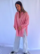 Camisa oversize a rayas verticales azules y blancas, con cuello clásico y cierre frontal con botones.