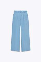 Pantalón celeste de tiro alto con cintura elástica ajustable con cordones, bolsillos delanteros y traseros, y pernera ancha.