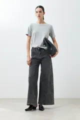 Pantalón de jean gris oscuro, corte wide leg, con tachas plateadas en los laterales.