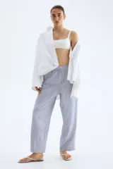 Pantalón tobillero de corte holgado en tejido liviano de mezcla de lino a rayas verticales azules y blancas. Modelo de tiro alto con elástico revestido y cordón para ajustar fino en la cintura, bolsillos al bies y piernas ajustadas.