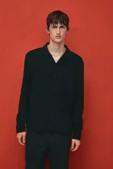 Camisa negra de tejido suave con cuello abierto, tapeta lisa y canesú en la espalda. Modelo de manga larga con cierre ajustable de botones en los puños y tapeta con botón. Bajo recto y corte estándar.