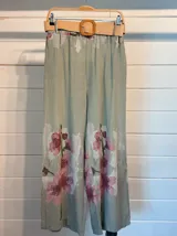 Pantalón palazzo verde claro con estampado de flores rosas, cintura elástica y lazo ajustable.