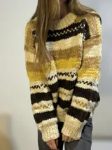 Sweater de lana merino con cuello redondo y diseño con motivos geométricos en tonos azul, marrón, naranja, verde y beige.