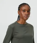 Blusa de viscosa color verde militar, de manga larga y cuello redondo. Presenta corte peplum con volado en el bajo y textura acanalada.