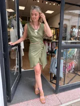 Falda corta cruzada color verde militar con brillo sutil, confeccionada en lino con lurex. Incluye una hebilla decorativa que permite ajustar el calce.