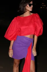 Falda violeta de lino, corte mini con diseño cruzado y lazo lateral rojo.