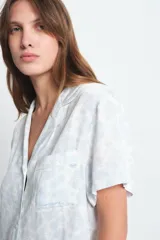 Conjunto de pijama de viscosa color blanco con estampado floral celeste, compuesto por una camisa de manga corta con cuello y botones, y un short con cintura elástica.