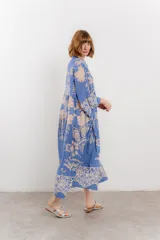 Vestido largo azul con estampado floral en tonos beige, confeccionado en viscosa. Presenta escote en V, botonadura completa en el frente y mangas largas con volados.