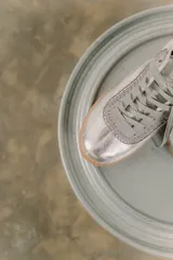 Zapatilla plateada de cuero con detalles de gamuza gris y costuras visibles.