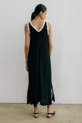 Vestido midi negro con escote en V, breteles finos con volados blancos y tajos laterales.