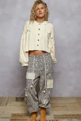 Campera corta color crema con textura waffle, capucha ajustable con cordones y cierre frontal con botones. Presenta bolsillos con solapa en el pecho y mangas amplias con puño elástico.