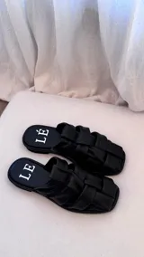 Sandalias bajas color rosa viejo con tiras de cuero entrelazadas y suela marrón.