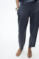 Pantalón color arena de tiro medio con cintura elástica, bolsillos laterales ocultos y pinzas en el delantero.