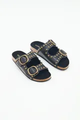 Sandalias negras de cuero con tachas metálicas y hebillas doradas. La plantilla es de corcho y la suela de goma eva.