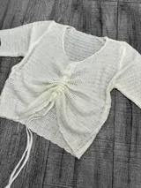 Remera calada color crudo, de hilo con escote en V y mangas cortas.