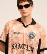 Remera masculina oversized de poliéster con cuello en V y solapa. Presenta mangas cortas, estampa angelical y lettering.