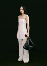 Mono largo blanco, strapless, de corte recto y con aberturas en el bajo. Cierre de cremallera en la parte posterior y forro interior.