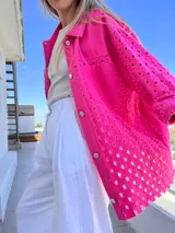 Camisa fucsia con calados, de corte recto, con cuello camisero, cierre frontal con botones y bolsillo de parche en el pecho.