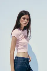 Camiseta rosa de algodón y modal, corte slim fit, cuello redondo, manga corta y largo crop. Estampado frontal con la frase "Old Sacramento CALIFORNIA UNITED STATES, EST. 1974" en color marrón.