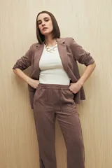 Pantalón beige de tiro medio con cintura elastizada y cordón regulable, bolsillos laterales y calce relajado.
