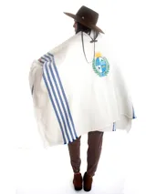 Poncho blanco con rayas azules y escudo patrio bordado.