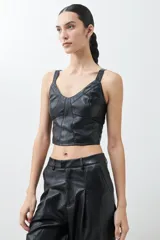 Top negro de eco cuero con corte crop, breteles finos y detalle de tul en el escote.